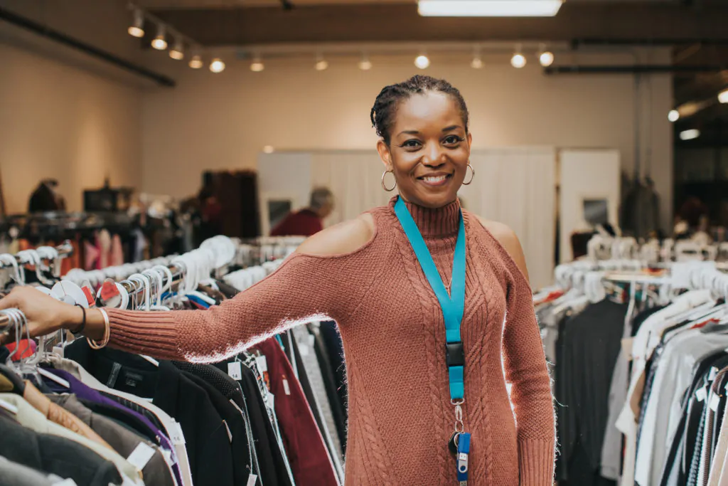 A person at work in Goodwill, with garment racks in the background