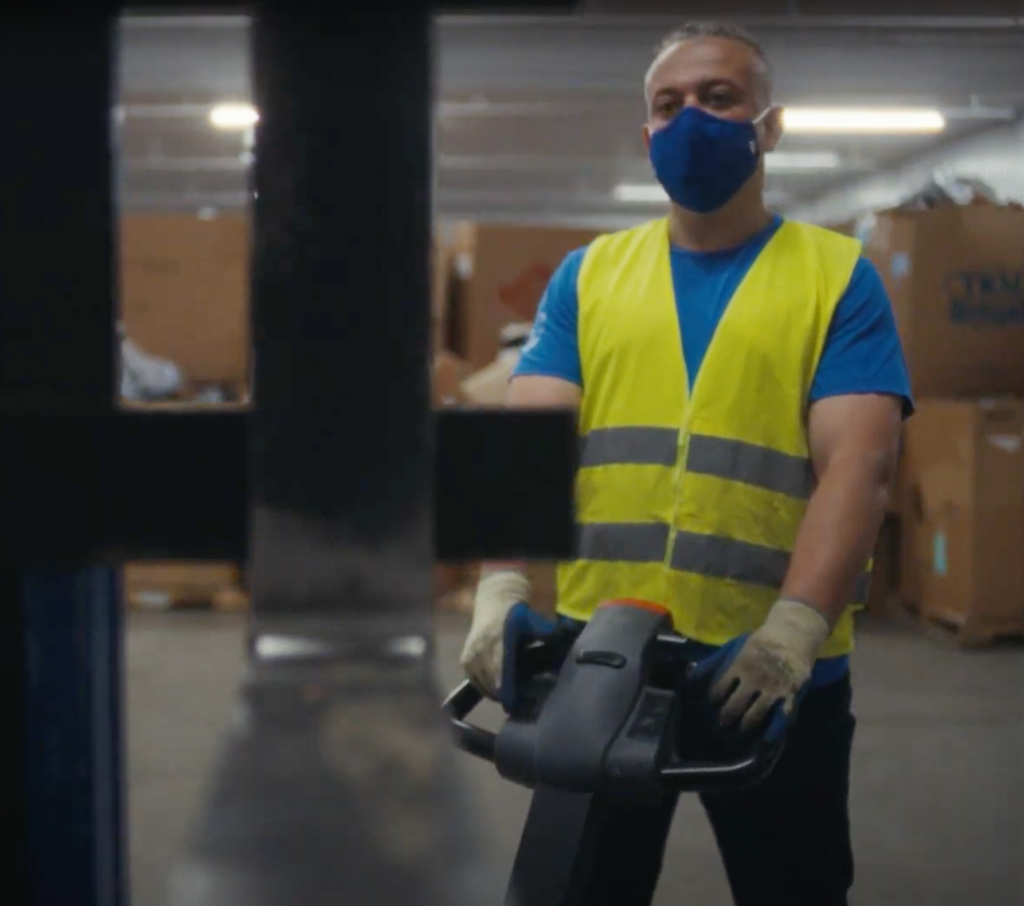 An equipment operator moving boxes of donated goods in a facility