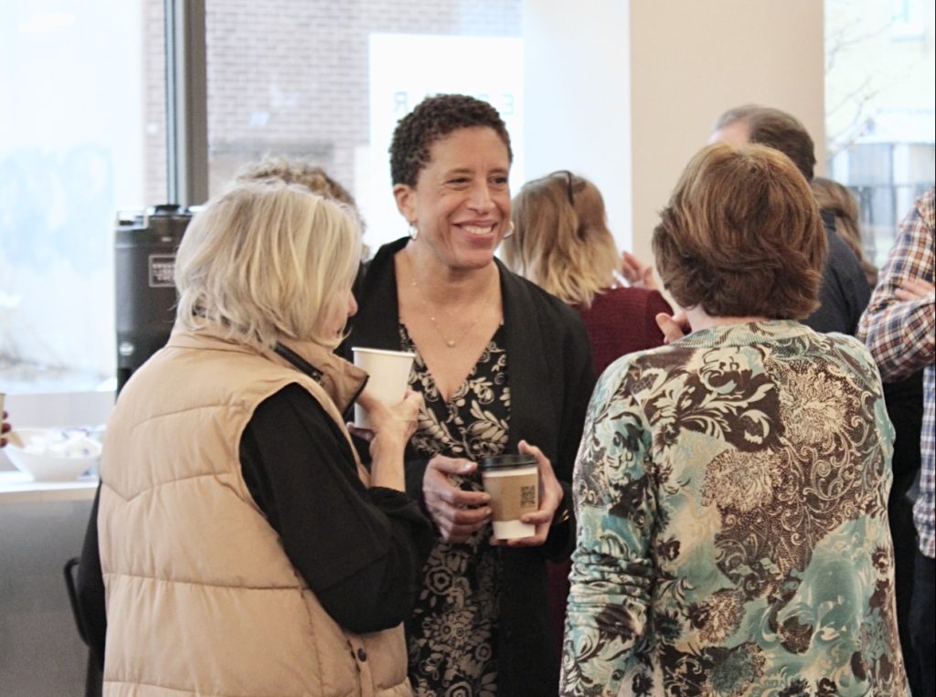 Three people laugh and drink coffee at Edgar and Joe's Café.